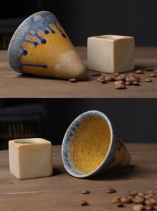 Macro detail of hand-poured blue and yellow glazed ceramic coffee dripper on wooden table