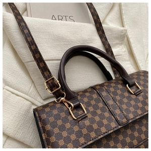 Close-up of vintage patterned brown satchel with gold hardware and smooth handle