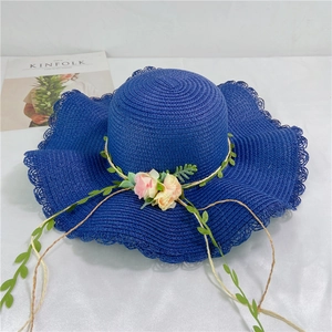 Detail of navy blue woven sun hat featuring pink flower decor and wavy brim edges