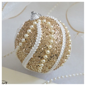 Close-up of champagne gold glitter Christmas ball with white pearls and sequins