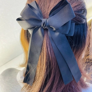 Elegant large black satin ribbon bow hair clip worn on brown hair for a chic look