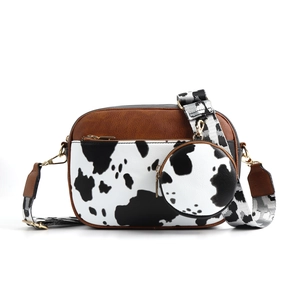 Detail of crossbody camera bag with cow print fabric and brown leather trim