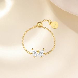 Macro shot of S925 engraved gold chain ring with butterfly zircon charm detail