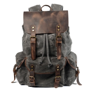 Retro grey canvas backpack with brown leather accents and multi-pocket design on white background