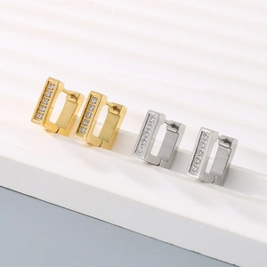 Macro detail of square stainless steel hoop earrings in gold and silver with zircon