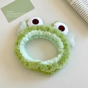 Détail d'un bandeau grenouille en peluche verte fait main avec de grands yeux