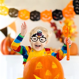 Detail of child wearing Halloween paper glasses with black cat and witch pot designs