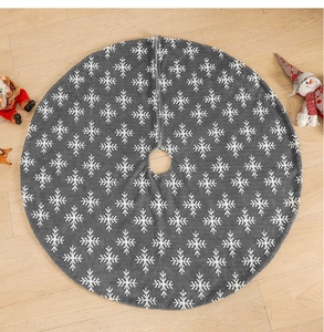 Detail of grey plush Christmas tree skirt with white snowflake patterns on wood floor