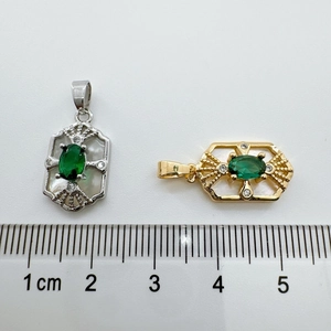 Detailed size comparison of 18K gold and silver shell emerald pendants with a ruler