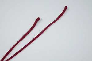 Detail of slim deep red knitted straps with refined stitching on a white backdrop