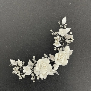 Macro detail of bridal hair piece with white ceramic roses, silver leaves and pearls