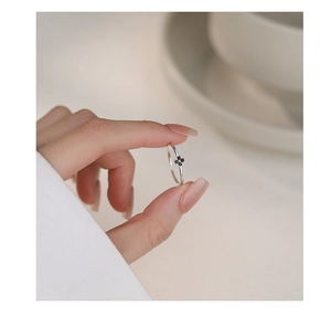 Close-up of minimalist S999 silver ring with black four-leaf clover gem on a finger
