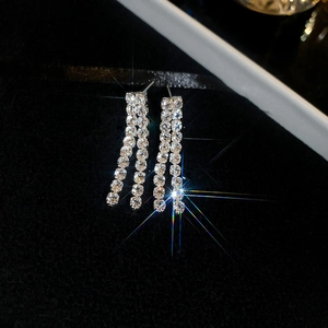 Macro shot of silver zircon tassel earrings sparkling on black velvet background