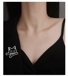 Detailed close-up of a black cat enamel pin with knife on a black suit lapel