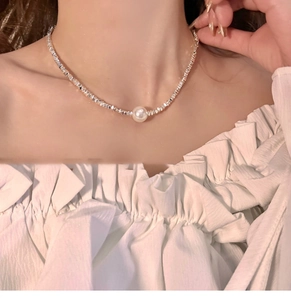 Detail of silver beaded necklace with white pearl pendant worn on model neck