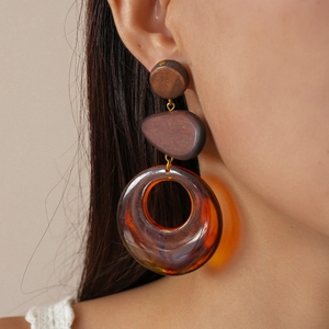 Detail view of ethnic resin wood grain earrings with amber ring drop on a model