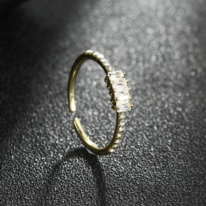 Bague dorée ajustable avec pierres taille baguette et cristaux sur fond noir texturé