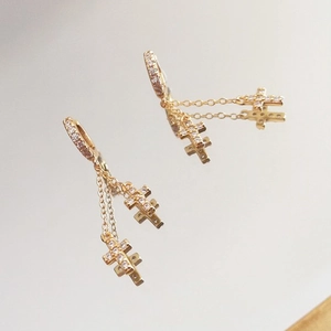 Macro shot of gold-plated hoop earrings with cubic zirconia encrusted cross charms