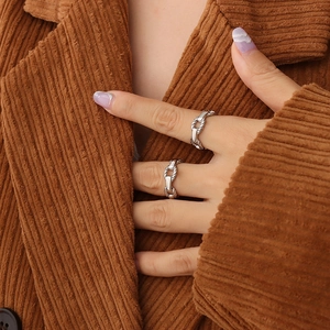 Minimalist silver chain link adjustable rings worn on fingers against a brown background