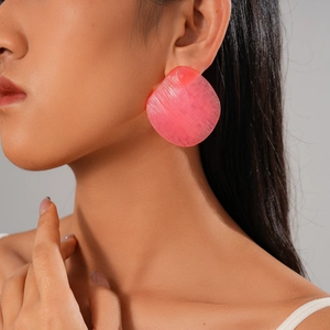 Pink resin geometric round earrings with textured pattern on female model
