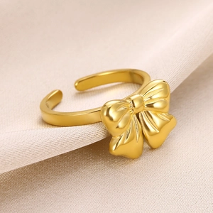 Macro shot of gold bow knot ring with textured detail on satin background
