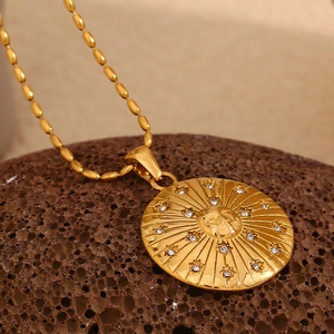 Detail of 18K gold plated sun face relief pendant with small crystals on lava rock