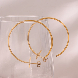 Macro detail of large gold hoop earrings with star studs displayed on a glass rim