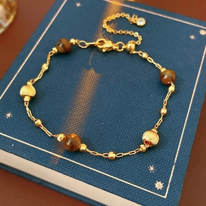 Detail of gold-plated bracelet with tiger eye beads on a blue jewelry box