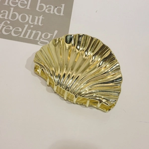 Detailed view of a golden shell-shaped metal hair claw clip with a polished finish