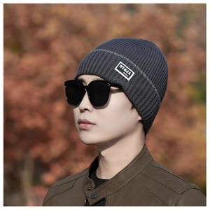 Detail of grey ribbed knit beanie with NY&JA logo patch on a model with sunglasses