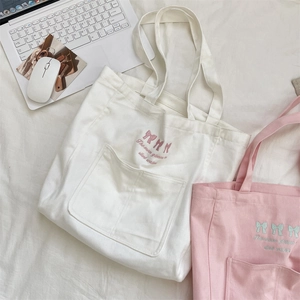 Detail of embroidered bow and quote on canvas tote bag with large front pocket