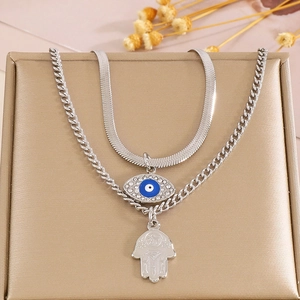 Detail of silver double-layer necklace with blue evil eye and Hamsa hand on jewelry box