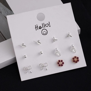 Set of six silver earrings with pearls and purple gems on a white display card