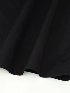 Close-up of the smooth black draped hemline with detailed stitching on a resort dress