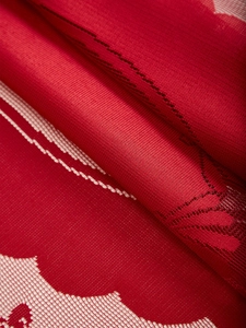 Macro shot of red Christmas lace tablecloth fabric with detailed mesh texture and patterns