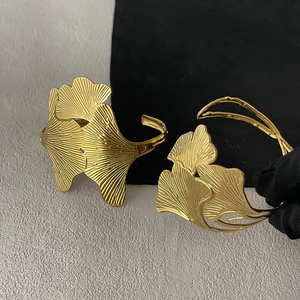 Detailed macro shot of the ginkgo leaf texture on a golden stainless steel cuff bracelet