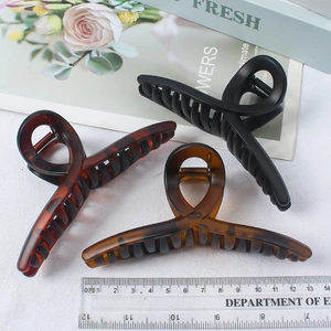 Three large matte black and leopard print hair claw clips measured with a scale ruler