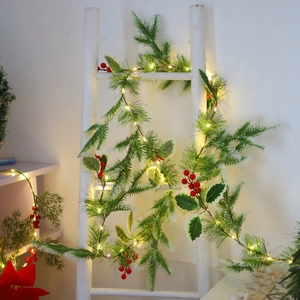 Christmas pine garland with red berries and warm LED lights on a white decorative ladder