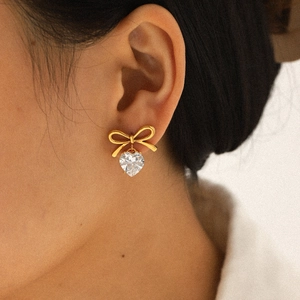 Golden bowknot earrings with heart-shaped zircon drop pendant worn by model