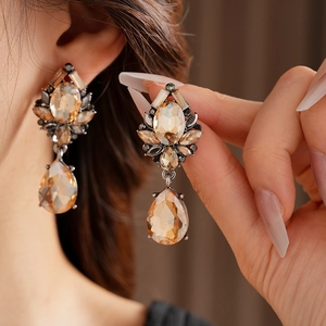 Macro shot of vintage teardrop earrings with amber stones and black gems on model
