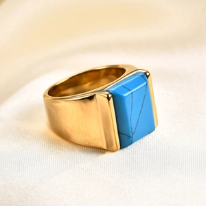 Makroaufnahme: Goldener 10mm Edelstahlring mit quadratischem Türkis auf Seidenstoff