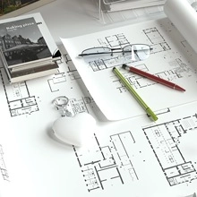 Detail of white heart-shaped wireless key finder on architectural drawings with glasses
