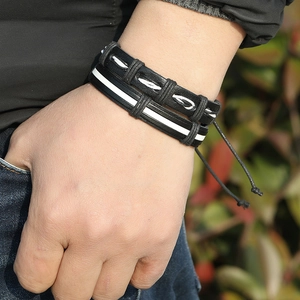 Close-up of multilayered black and white woven leather bracelets with adjustable drawstrings