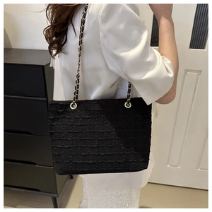 Detail of black tote bag with textured plush finish and gold-silver chain strap