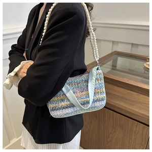 Close-up of colorful striped woven handbag with pearl strap and pink butterfly embroidery