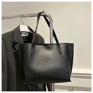 Detail of matte black leather tote bag with long straps paired with professional suit