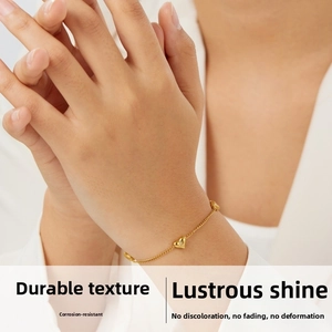 Close-up of a gold-plated heart bracelet with sparkling diamond accent on a model's wrist