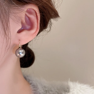 Close-up of deep grey pearl drop earrings with minimalist golden geometric hooks