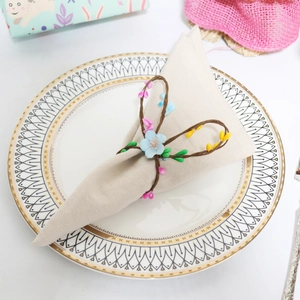 Close-up of handmade floral napkin ring with berries on a linen napkin and white plate