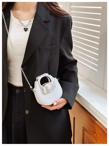 Mini white chain bag with silver handle shown worn over a black blazer for styling